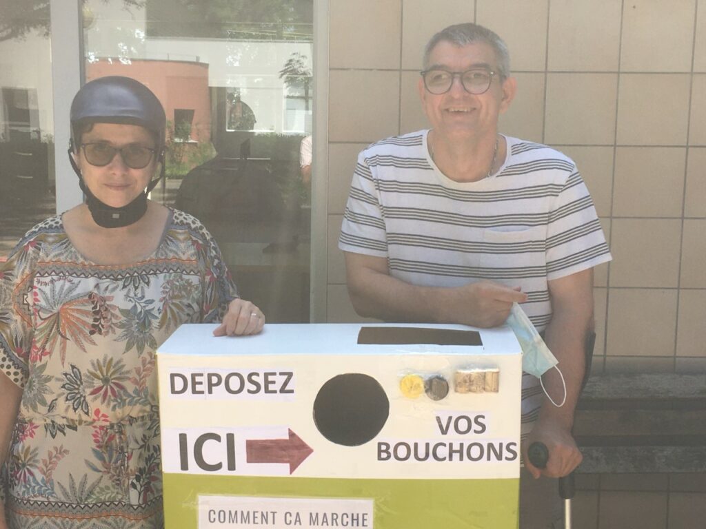 Chloé et Vincent, résidents d'Arceau devant un boite de collecte de bouchons 